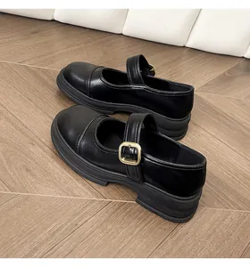 Close-up of black Mary Jane shoe featuring a thick platform and a gold buckle detail