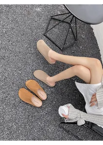 Platte suède instappers in bruin en beige op grijze steen met koffiekopje decoratie
