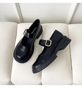 Detail of glossy black Mary Jane loafers featuring thick platform soles and gold buckles