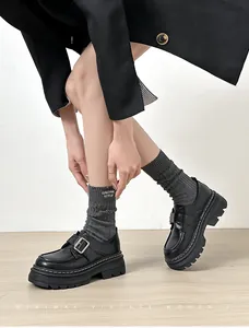 Detalle de mocasines de plataforma negros con costuras blancas y hebilla de metal plata