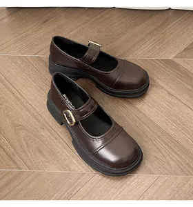 Close-up of brown Mary Jane leather shoes with thick soles and gold buckles on wood floor