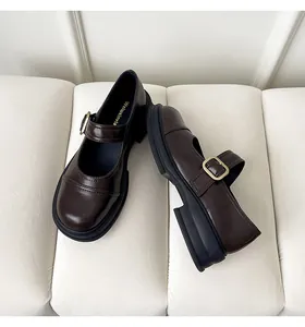 Detailed top view of dark brown Mary Jane shoes with thick soles and gold buckles