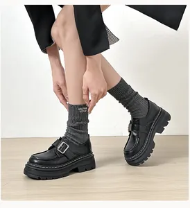 Primer plano de mocasines negros de plataforma con hebilla plateada y suela gruesa