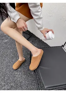 Klassieke kaki suède muiltjes voor dames gedragen in een stijlvolle buitenomgeving