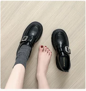 Vista superior de mocasín negro con plataforma, hebilla plateada y costura blanca