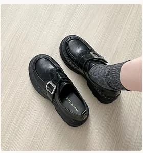 Primer plano de mocasines negros de plataforma con hebilla plateada y cuero mate