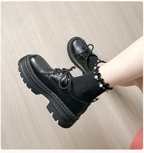 Detalle de mocasines negros de plataforma con suela dentada y calcetines con perlas