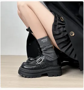 Vista lateral de mocasines negros con plataforma, hebilla de metal y calcetines Grunge