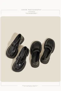 Macro shot of glossy black platform loafers featuring chunky serrated soles and round toe
