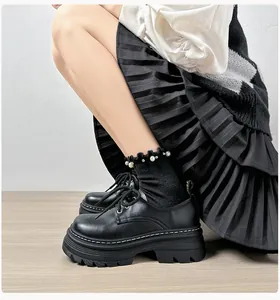 Detalle de mocasines negros de plataforma con cordones y calcetines con perlas y volantes