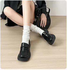 On-foot view of black platform loafers paired with white textured mid-calf socks