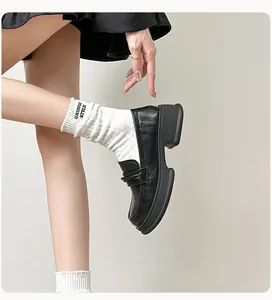 Detail shot of glossy black platform loafers with classic wedge sole and stitched leather design