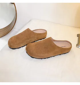 Detailopname van bruine suède muiltjes met een stevige zwarte rubberen zool