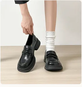 Detailed view of black platform loafers with thick soles and stylish cross strap design