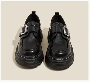 Detalle de mocasín negro de plataforma con hebilla de metal y costuras en contraste