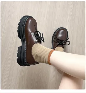 Detalle de mocasines Oxford marrón oscuro con suelas de plataforma y costuras blancas