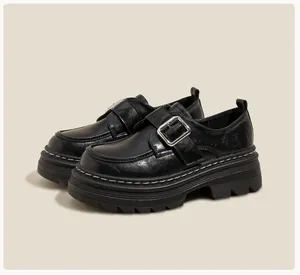 Detalle de mocasines negros con plataforma textura de cuero y hebilla plateada