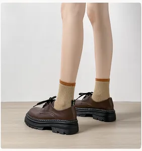 Detalle de mocasín marrón con plataforma, costuras en contraste y tirador de talón