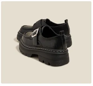 Vista lateral detallada de los mocasines con plataforma en cuero negro y hebilla