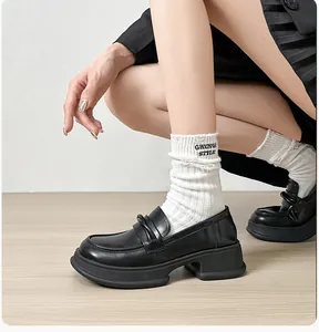 Detail of black platform loafers and white grunge style socks with embroidery