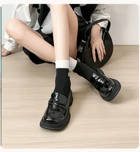 Close-up of black patent leather chunky platform loafers with retro British style design
