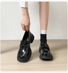 Detail of glossy black patent leather loafers with woven strap and platform sole