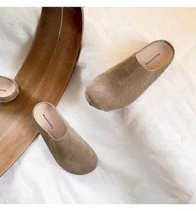 Detailopname van camel lederen muiltjes met zachte suède afwerking en logo inlegzool