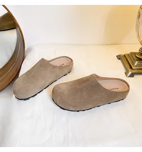 Detailopname van kaki suède instapklompen met ronde neus en lederen voetbed op schoon textiel
