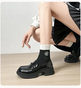 Detail of black patent leather platform loafers with decorative knot and thick rubber soles
