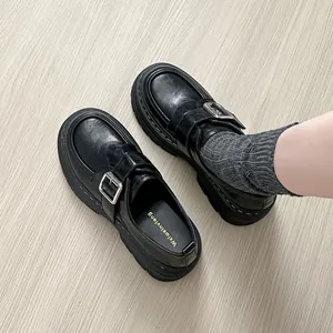 Mocasines clásicos negros con plataforma y hebilla plateada sobre suelo de madera