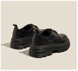 Detalle de mocasín negro con plataforma, costuras blancas y tira decorativa