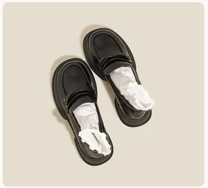 Top view of shiny black platform loafers with classic strap and white lace socks