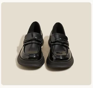 Front view of black patent leather platform loafers with decorative knotted straps