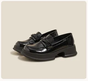 Detailed 45-degree angle of shiny black patent leather platform loafers with chunky soles