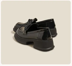 Detailed side view of black patent leather platform loafers with thick wedge soles