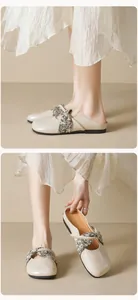 Close-up of beige flat mule shoes with elegant floral fabric strap and soft leather finish