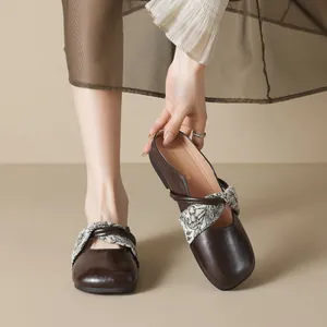 Brown square toe flat mules with decorative cross straps and a polished leather finish