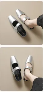 Detail of silver square-toe mule slippers featuring a sparkling rhinestone-embellished buckle