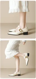 Detail of cream pointed-toe Mary Jane shoes with buckle strap and black block heels