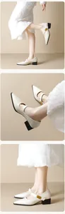 Close-up of cream pointed-toe Mary Jane shoes featuring a gold buckle with fashion engraving