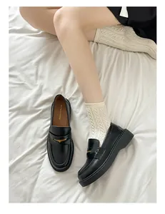 Macro detail of black leather loafers with gold buckles and platform soles on white socks