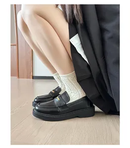 Detail of black platform loafers featuring a golden triangle buckle and white knit socks