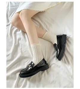 Detail of black patent leather loafers with thick soles and round toes in retro style