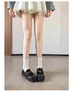 Close-up of black platform loafers with gold metal buckle worn with white lace skirt