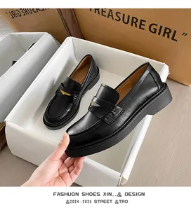 Detail view of black leather platform loafers showing the chunky sole and gold buckle trim