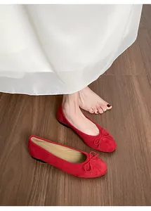 Vue de dessus de ballerines en daim rouge à bout rond et nœud sur sol en bois