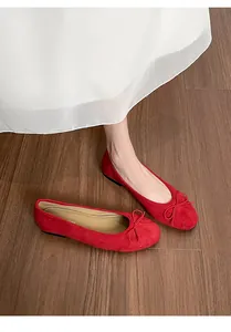 Gros plan de ballerines en daim rouge avec nœud délicat et bout rond classique