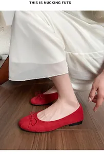 Gros plan de ballerines en daim rouge avec nœud sur le bout rond et semelle noire