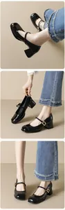 Detail of black glossy Mary Jane shoes with thick heels and gold metal buckle straps
