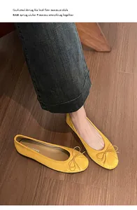 Vue de dessus de ballerines jaunes en daim avec nœud et bout rond sur parquet en bois